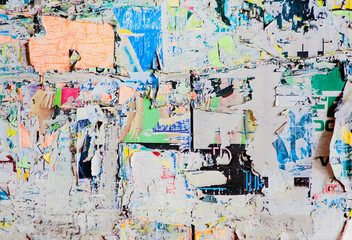 An unintended collage art poster, made by different layers of worn and torn street ads on a city wall, accumulated over time.
