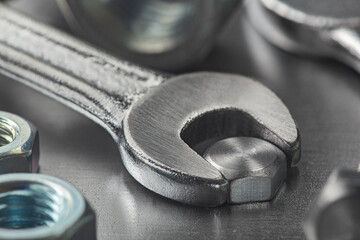 Wrench tightens bolt in steel billet. Spanner, bolt, screw and nuts.