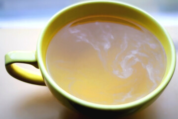 Book and big yellow cup of tea. Selective focus.
