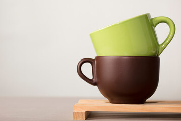 two brown and green cups of coffee or tea on wood with white background