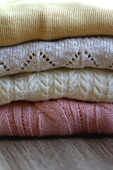 Pile of sweaters in pastel and neutral colors. Selective focus.