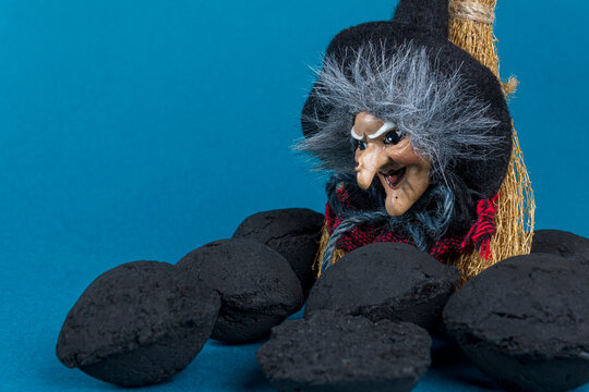 Epiphany holiday concept. Witch Befana and coal pieces for naughty kids on blue background. Copy space.
