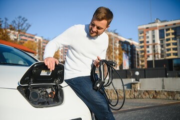 Man charges an electric car at the charging station