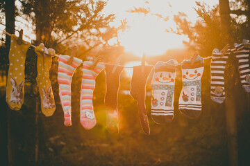Five pairs of novelty Christmas socks hanging on a clothes line in a garden drying in the afternoon sun