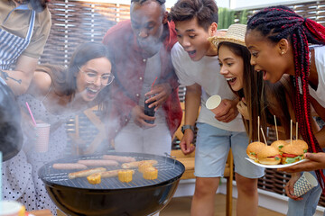 Group of friends in casual clothes making meal on barbecue grill, diverse people on picnic on...