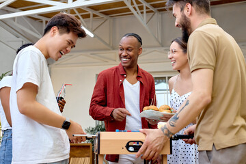 Excited students play kicker table football soccer outdoors in backyard during bbq barbecue party....