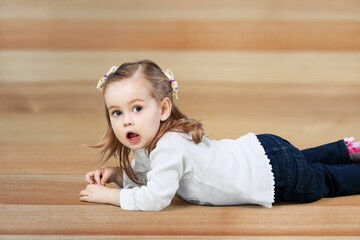 Naklejka premium Lying on floor. Little smiling cute child. Concept of emotions, facial expressions.