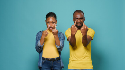 African american couple showing rude middle finger in front of camera. Man and woman advertising...