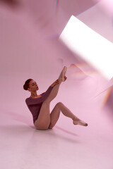 Caucasian ballerina putting ballet shoe on her leg