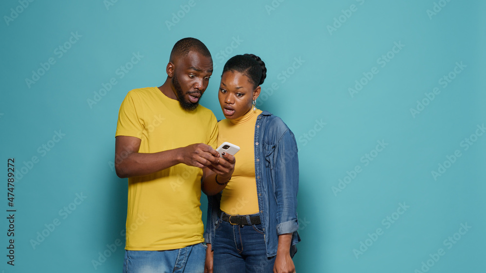 Poster man and woman using internet on smartphone together in front of camera. people looking at mobile pho