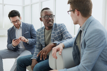 Image of young colleagues standing in office and talking with each other