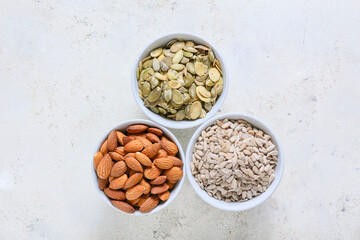 Bowls with sunflower, pumpkin seeds and almond nuts on grunge background