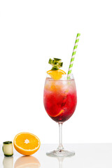 glass with red drink decorated with orange and cucumber on white background.