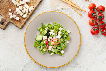 Plate with healthy Greek salad on light background