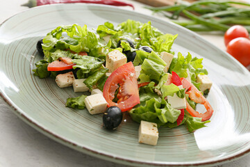 Plate with healthy Greek salad on light background, closeup