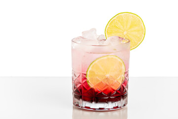 Red drinking glass, gin, tonic water, granadina,  decorated with lemon on a white background.