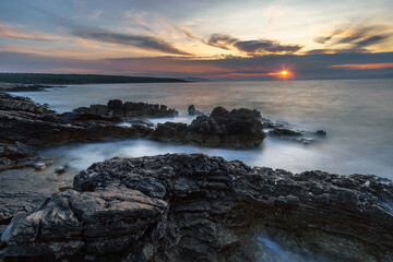 Fototapeta na wymiar long exposure of waves on rocks during sunrise over the sea on summer morning in Croatia.