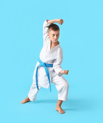 Little boy practicing karate on color background