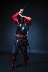 A man in samurai armor holds a sword over his head