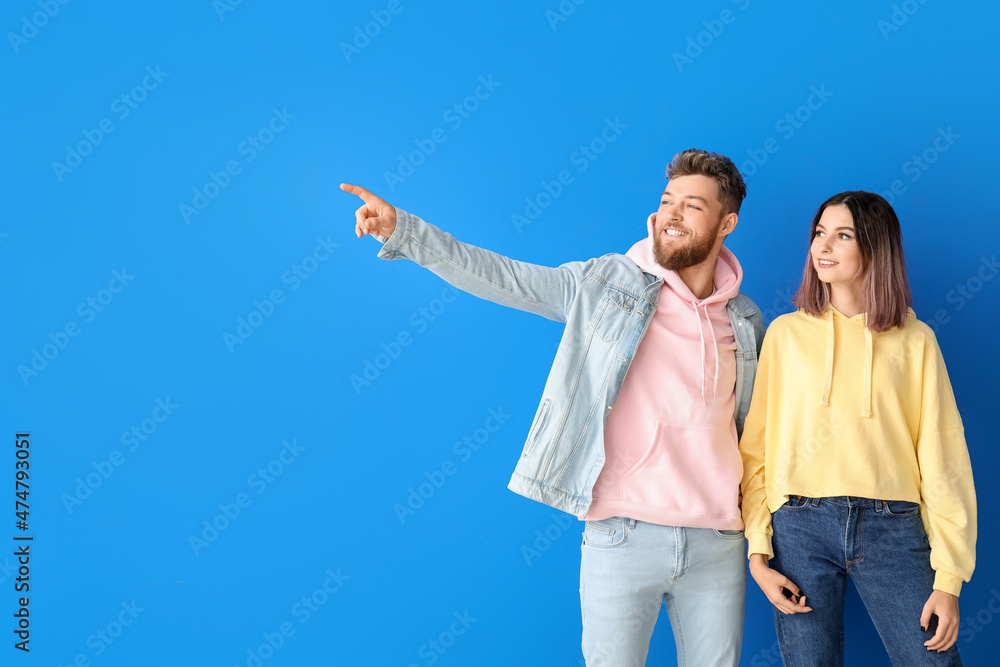 Wall mural cool young couple in hoodies on color background - Wall murals
