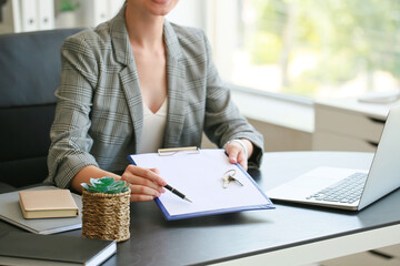 Real estate agent with clipboard and key from house in office