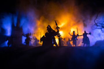 Medieval battle scene with cavalry and infantry. Silhouettes of figures as separate objects, fight between warriors on dark toned foggy background with medieval castle.