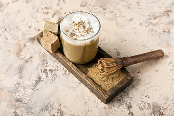 glass of hojicha latte, chasen, powder and marshmallows on grunge background