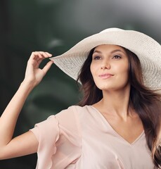Stylish girl posing against the wall. Photo of a woman in a hat.