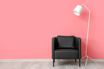 Modern black armchair and white standing lamp near pink wall