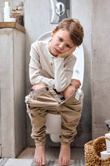 School boy is sitting on toilet with suffering from constipation or hemorrhoid. caucasian kid is on...