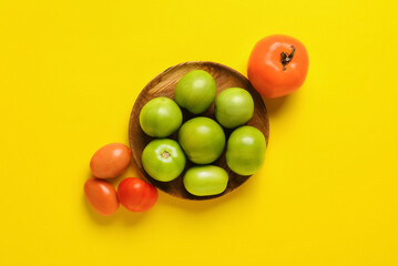 Green and ripe tomatoes on color background