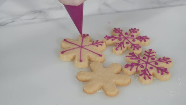 Step by step. Icing snowflake shaped sugar cookies with pink royal icing.