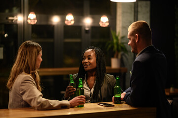 Cheerful colleagues drinking beer in the bar together after work