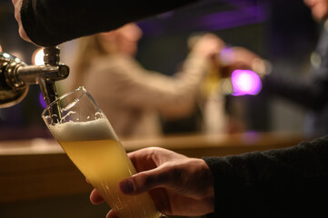 Hand of bartender using beer tap while working in a bar