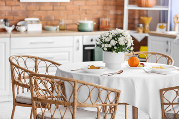 Dining table with beautiful Chrysanthemum flowers in interior of modern kitchen