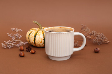 Cup of tasty pumpkin coffee on brown background