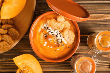 Bowl with delicious pumpkin cream soup on wooden background