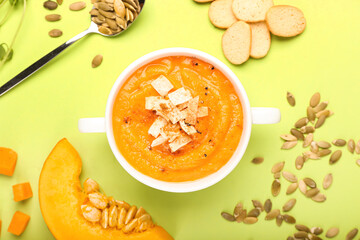 Composition with delicious pumpkin cream soup and seeds on color background
