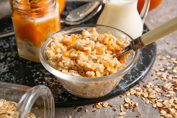 Bowl of tasty oatmeal with pumpkin on grunge background