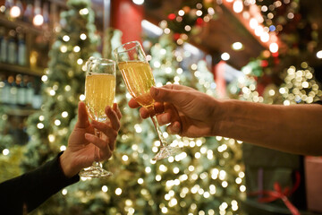Two hands with glasses of champagne on a Christmas or New Year background