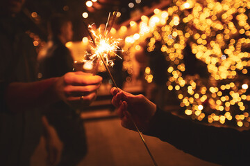 Two hands with sparklers on a Christmas or New Year's eve background