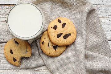 Tasty homemade cookies with chocolate chips and glass of milk on light wooden background