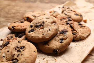 Parchment with tasty homemade cookies on wooden background, closeup