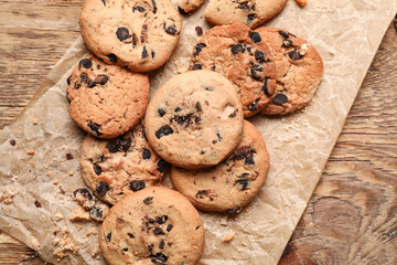 Parchment with tasty homemade cookies on wooden background