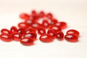 Krill oil red gelatin capsules set on a white wooden background .omega fatty acids.
