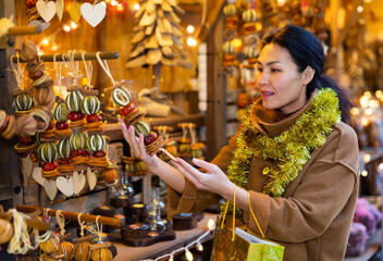 Fototapeta premium Smiling asian woman customer near counter with Christmas gifts at Christmas market