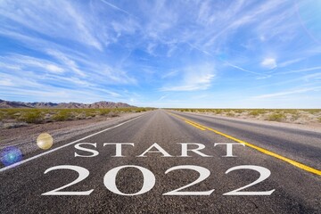 Start 2022 written on highway road in the middle of empty asphalt and beautiful blue sky.