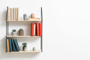 Modern shelves with books hanging on light wall