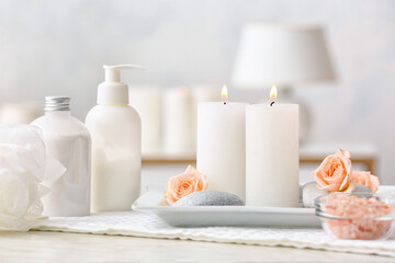 Spa set with burning candles on light background