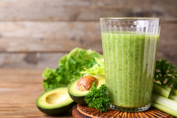 Glass of healthy green smoothie and vegetables on wooden background